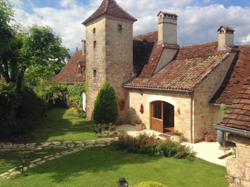 Manoir De Rieuzal stone manor with towers in Loubressac, France surrounded by green gardens and flowers