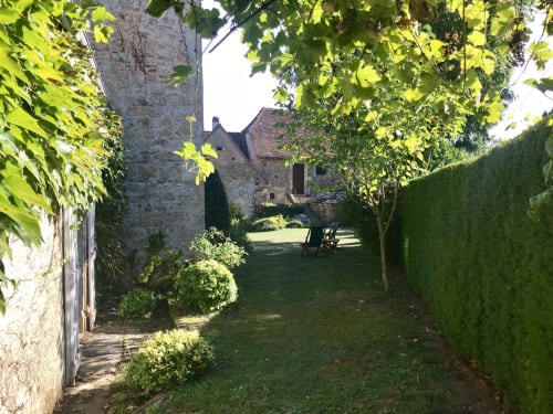 Lush garden pathway at Manoir De Rieuzal, a French B&B in Loubressac with stone buildings and hedges
