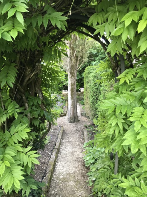 Lush garden pathway at Manoir de Rieuzal, Loubressac, with verdant foliage and stone arch