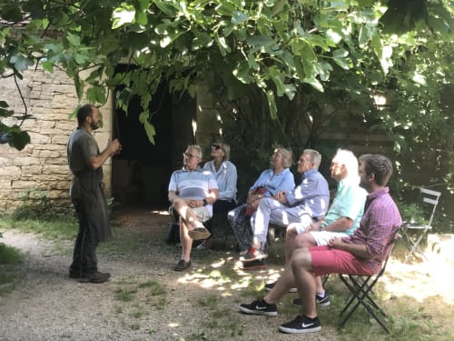 Guide leading tour group in shaded garden at Manoir De Rieuzal B&B, Loubressac