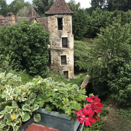 Historic stone tower at Manoir De Rieuzal in Loubressac, surrounded by lush gardens and ivy