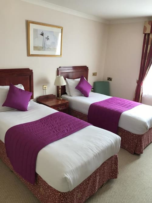 Chambre twin de l'hôtel La Trelade, St Martins avec accents violets, lits en bois foncé et literie crème