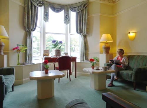 Élégant salon de l'hôtel La Trelade à St Martins aux murs jaunes, baies vitrées, canapés verts et mobilier traditionnel
