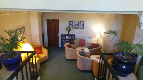 Le salon de l'hôtel La Trelade avec fauteuils crème, bibliothèques et plantes en pot à St Martins