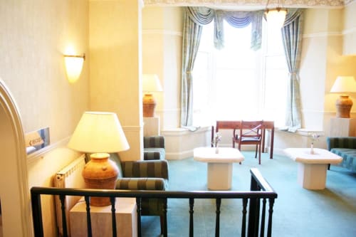 Élégant salon d'hôtel à la Trelade à Saint-Martin avec murs crème, sièges rayés, moquette bleue et grands rideaux