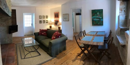 Spacious sitting room with gray sofa, dining table, and wooden chairs at Manoir De Rieuzal in Loubressac, France