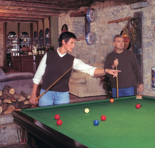 Deux hôtes jouant au billard au Château d'Hassonville, un gîte belge à Marche-en-Famenne, avec murs en pierre