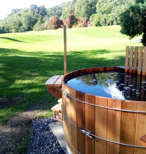 Baignoire en bois dans un jardin luxuriant au Château d'Hassonville, refuge champêtre belge