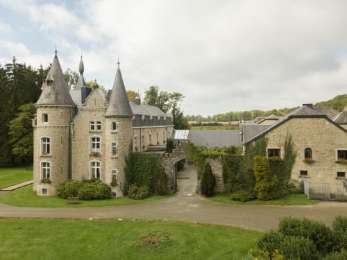 Château d'Hassonville, forteresse en pierre aux tourelles entourée de pelouses verdoyantes à Marche-en-Famenne, Belgique