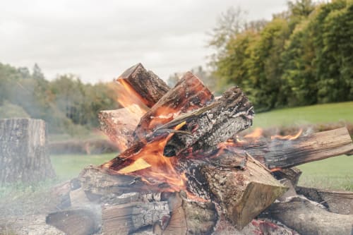 Crackling campfire with wooden logs and orange flames in rural Belgian countryside near Marche-en-Famenne