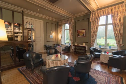 Elegant lounge with black leather armchairs and round tables at Château d'Hassonville, Belgium
