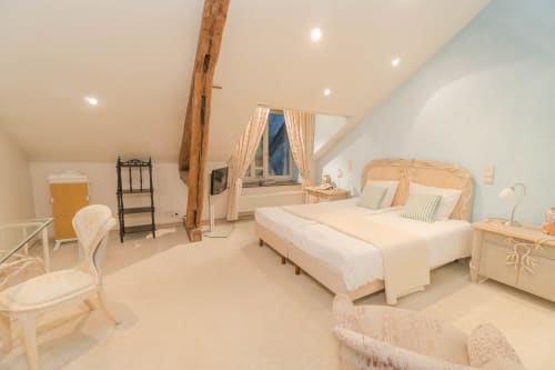 Spacious attic bedroom at Château d'Hassonville B&B in Marche-en-Famenne with exposed beams, two beds, and elegant décor