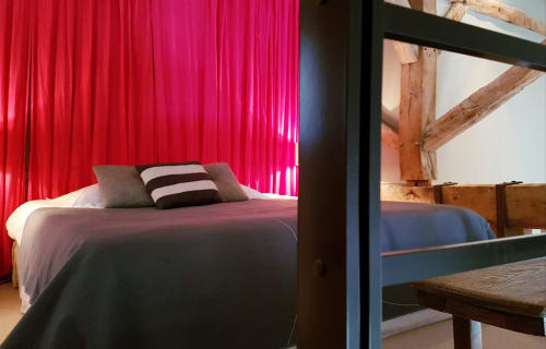 Modern bedroom at Moulin Renaudiots in Autun with neon pink lighting, dark bed frame, and rustic wooden beams