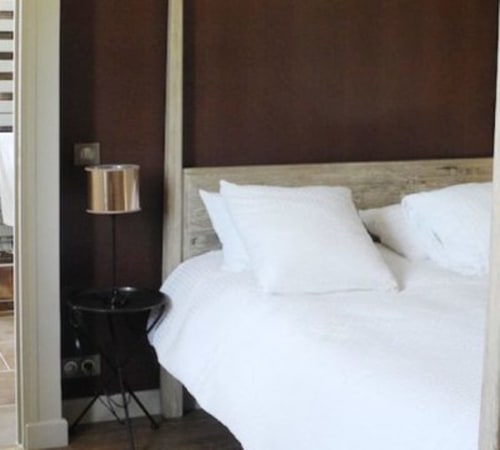 Modern hotel bedroom at Le château d'Hermonville with white bedding, wooden headboard, and dark burgundy accent wall
