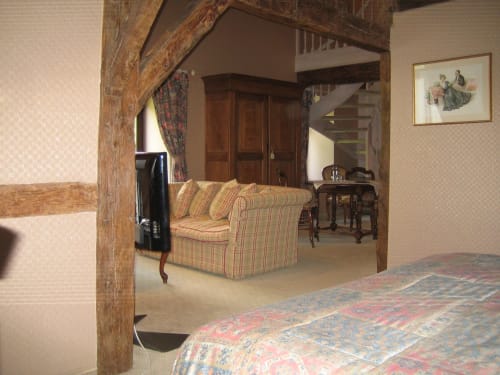 Suite Junior du Château d'Hassonville avec canapé rayé, poutres en bois et escalier à Marche-en-Famenne