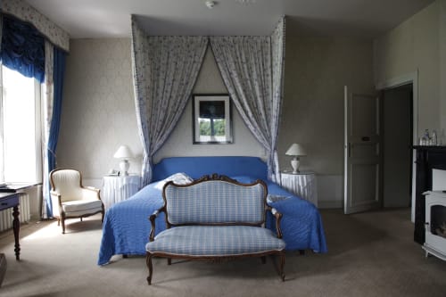 Suite junior élégante du Château d'Hassonville avec lit à baldaquin bleu, mobilier d'époque et vue sur les jardins à Marche-en-Famenne