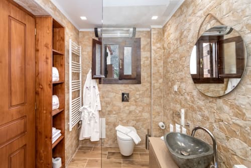 Modern bathroom at Villa Freedom with stone tiles, vessel sink, toilet, and shower in Kokkino Chorio, Crete