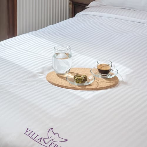 Bed at Villa Freedom Crete with water glass, coffee cup, and pastry on cork tray