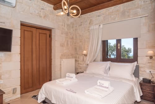 Bedroom at Villa Freedom in Kokkino Chorio, Crete with stone walls, wooden beams and sea view
