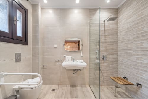 Modern bathroom at Villa Freedom in Crete with walk-in shower, white sink, and wood-look tile flooring