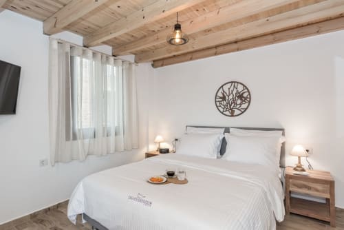 Modern bedroom at Villa Freedom in Kokkino Chorio, Crete with wooden beams, white bedding, and rustic decor