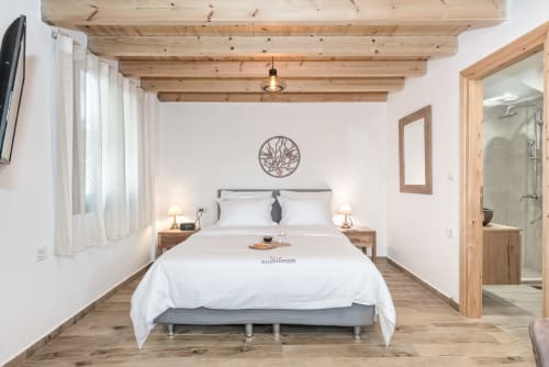 Modern bedroom at Villa Freedom in Kokkino Chorio, Crete with wooden beams, white bedding, and en-suite bathroom