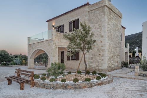Villa Freedom's stone exterior at dusk in Kokkino Chorio, Crete, with arched entrance and courtyard seating.