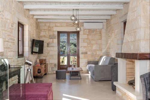 Villa Freedom lounge with stone walls, wooden beams, and modern furnishings in Kokkino Chorio, Crete