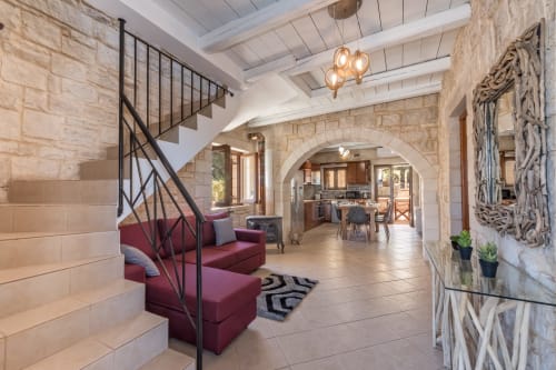 Villa Freedom luxury living room in Crete with stone arches, burgundy seating, and modern pendant lighting