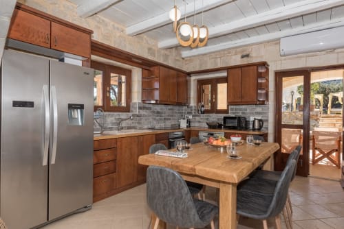 Modern kitchen and dining area at Villa Freedom in Kokkino Chorio, Crete with wooden cabinets and island table