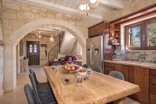 Open-plan kitchen and dining area at Villa Freedom in Crete with wooden table, stone archway, and modern appliances