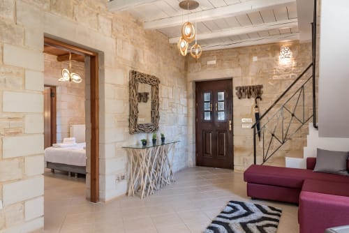 Villa Freedom foyer in Kokkino Chorio, Crete with stone walls, pendant lights, and burgundy seating area