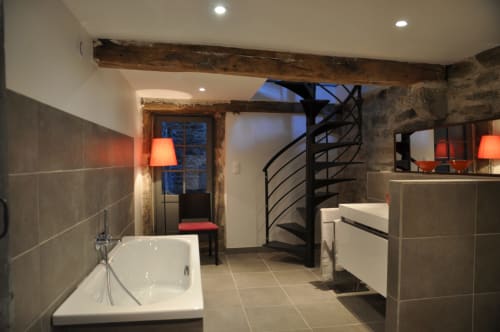 Modern bathroom with spiral staircase at Le Jardin De Beauvoir B&B in Lyon, featuring white bathtub and slate tiles