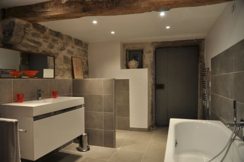 Modern bathroom with double vanity, freestanding tub, and exposed stone walls at Le Jardin De Beauvoir, Lyon