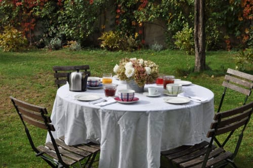 Outdoor breakfast setup at Le Jardin De Beauvoir with round table, white tablecloth, flowers, and pastries in Lyon garden