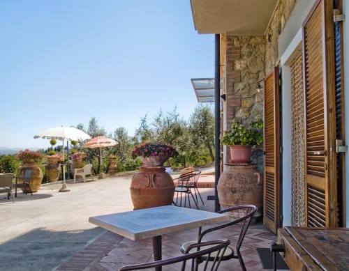 Terrazza toscana del B&B I Coppi a San Gimignano con pavimentazione in pietra, ombrelloni e vista sulla campagna