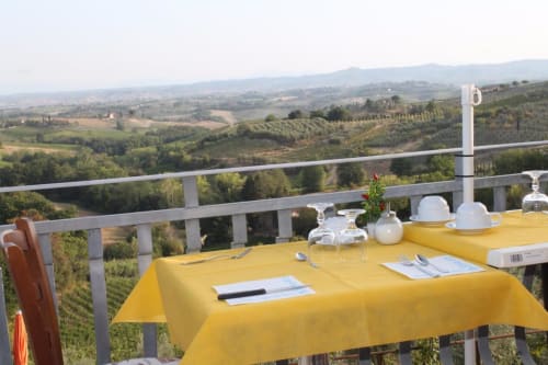 Tavolo con tovaglia gialla presso B&B I Coppi con vista sulla campagna toscana e i vigneti di San Gimignano