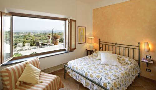 Camera doppia San Gimignano con terrazza, zona salotto a righe e vista sulla campagna