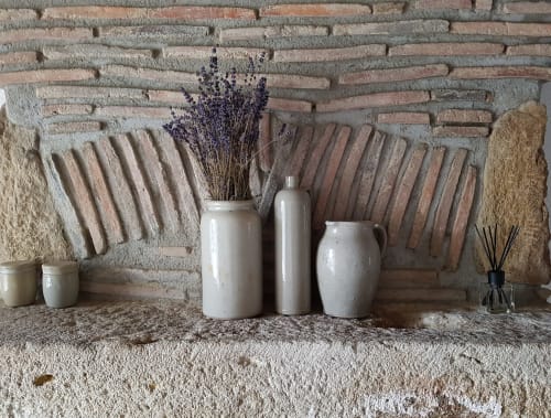 Rustieke bakstenen schoorsteenmantel in Moulin Renaudiots met keramische vazen, gedroogde lavendel en decoratieve accessoires