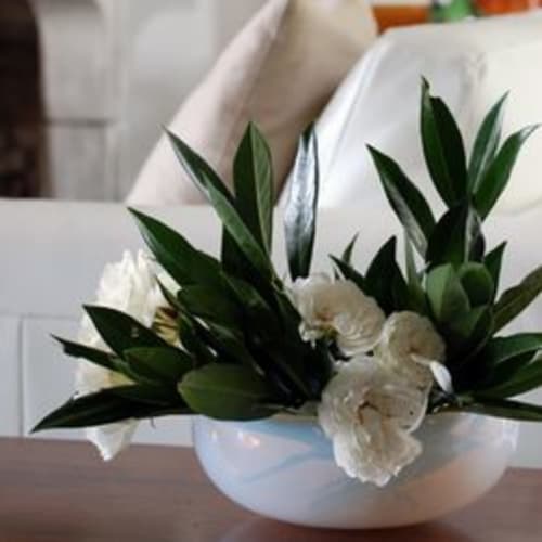 Witte rozen en groen bladwerk in een keramische schaal bij hotel Moulin Renaudiots, Autun