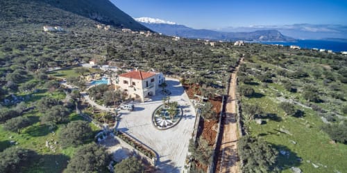 Aerial view of Villa Freedom B&B in Kokkino Chorio, Crete, showing white villa with red roof, courtyard, olive groves, and
