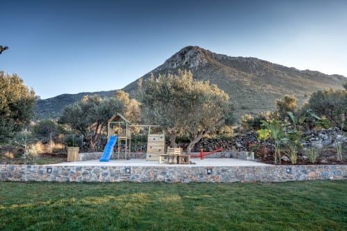 Wooden playground with blue slide and climbing equipment at Villa Freedom in Kokkino Chorio, Crete, mountains behind