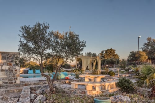 Villa Freedom's sunset pool courtyard with olive trees, stone architecture, and blue accents in Crete