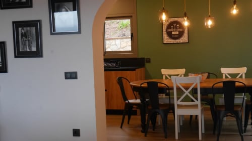 Dining area at Ty Pals B&B in Pals with green walls, wooden tables, mixed seating, and pendant lights