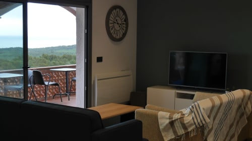 Ty Pals bedroom with sea view balcony, TV, clock, and striped blanket in Pals, Spain