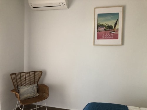 Cozy room at Ty Pals B&B in Pals with wicker chair, coastal-themed poster, and air conditioning unit