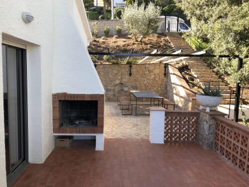 Outdoor terrace at Ty Pals villa in Pals with fireplace, dining furniture, and Mediterranean gardens