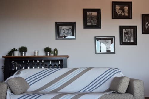 Stylish villa bedroom at Ty Pals with striped bedding, black framed family photos, and potted plants on wooden headboard