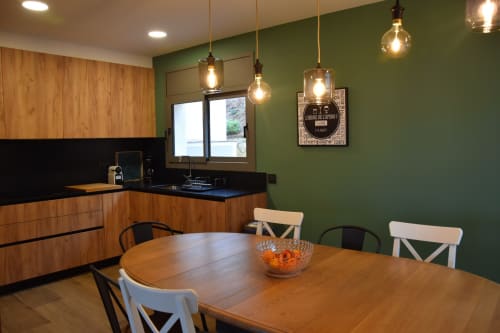 Modern kitchen and dining area at Ty Pals villa in Pals with green walls, wooden table, and pendant lighting