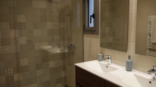 Modern bathroom in Ty Pals villa, Pals with dual sinks, patterned tile shower, and heated towel rack